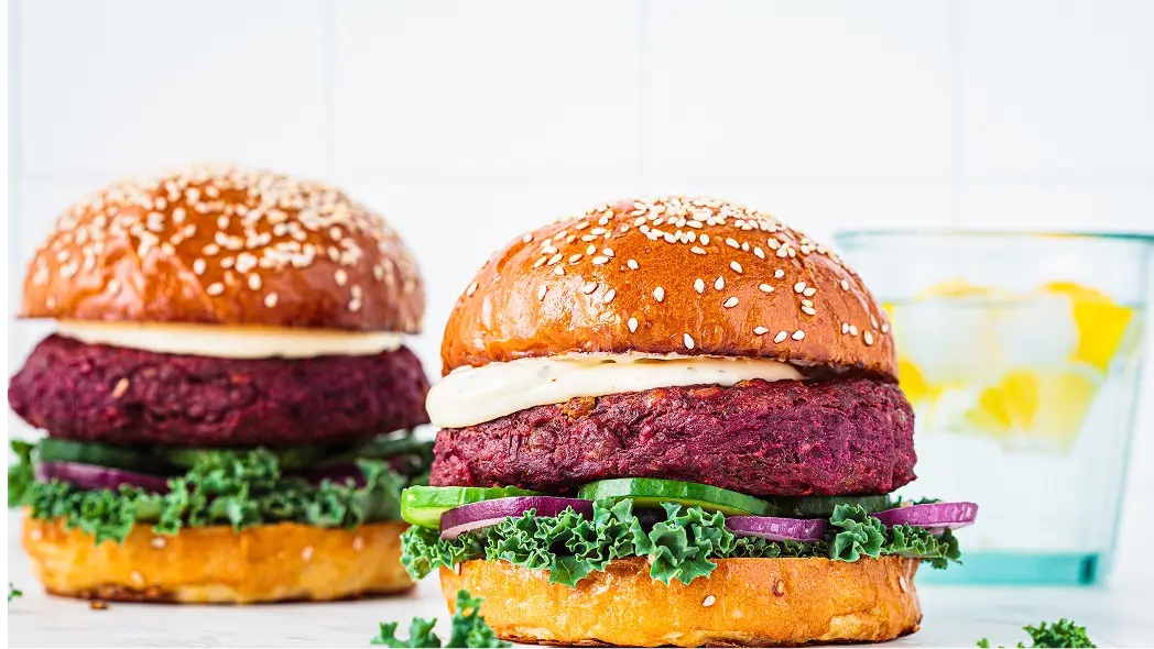 Hamburgueria plant-based servindo hambúrguer de beterraba com maionese vegana, couve, pepino e cebola roxa em pão com gergelim
