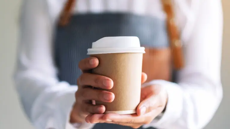Teknisa - Como abrir uma cafeteria do zero: Pessoa segurando copo de papel de café sustentável